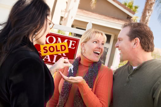 Hispanic Female Real Estate Agent Handing Keys to Excited Couple photo