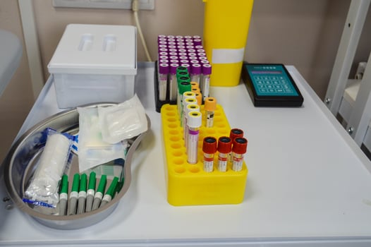 laboratory diagnostics. test tubes with multi-colored caps are in the holder. next to it is a medical vessel with needles and transfer material, tourniquets for a vein. taking venous blood photo