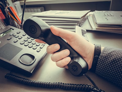 Closeup Of Businessman Holding Handset Of A Black Landline Telephone photo