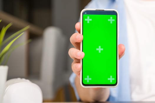 Mockup image of a man holding and showingsmartphone with green chroma screen photo