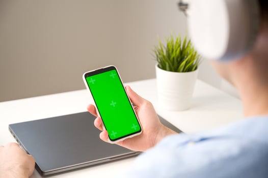 Asian man using smatphone with green chromascreen.Mockup photo