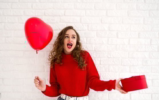Happy surprised woman holding gift and balloon. Women's or valentine's day concept. photo