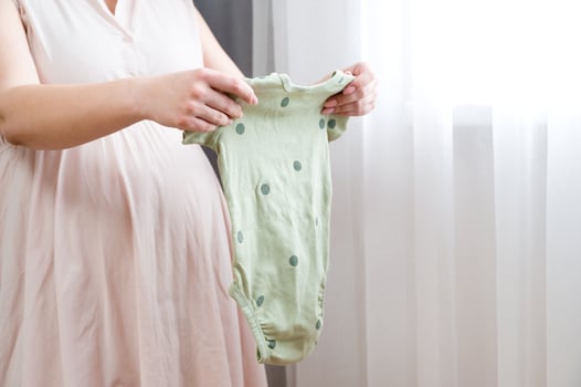 Pregnant woman preparing clothes for her baby. photo
