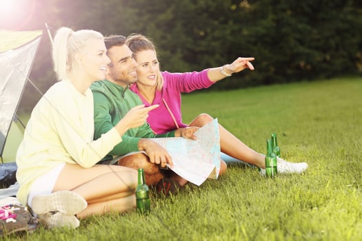 Group of friends camping in forest and looking at map photo