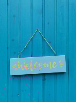 The welcome sign on the wooden blue door photo