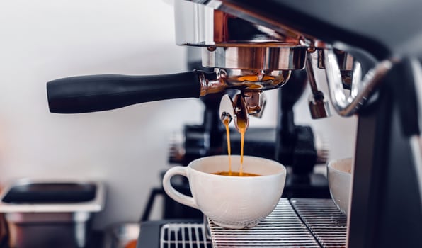 Coffee extraction from the coffee machine with a portafilter pouring coffee into a cup,Espresso poruing from coffee machine at coffee shop photo