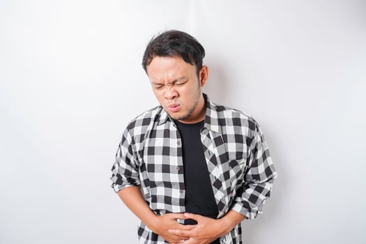 Photo of young unwell sick ill man hold hand on stomach suffers pain isolated on white background
