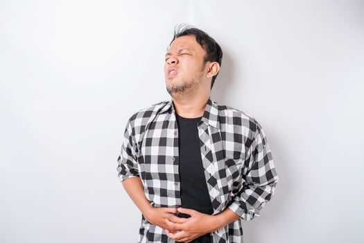 Photo of young unwell sick ill man hold hand on stomach suffers pain isolated on white background