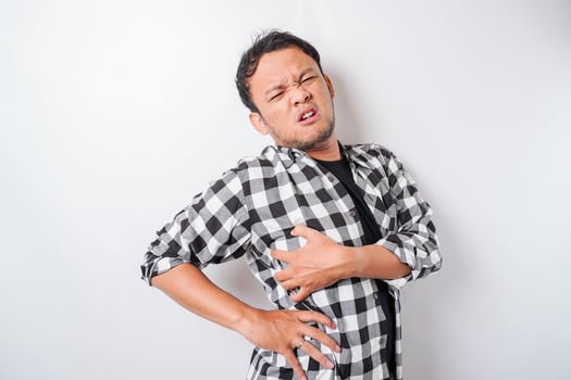 Tired upset young man suffering from back pain, muscle spasm at workplace. Fatigue, deadline, pain and incorrect posture photo