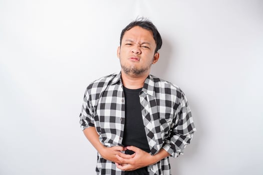 Photo of young unwell sick ill man hold hand on stomach suffers pain isolated on white background