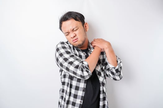 Tired upset young man suffering from pain, muscle spasm at workplace. Fatigue, deadline, pain and incorrect posture photo