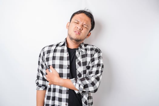 Tired upset young man suffering from back pain, muscle spasm at workplace. Fatigue, deadline, pain and incorrect posture photo