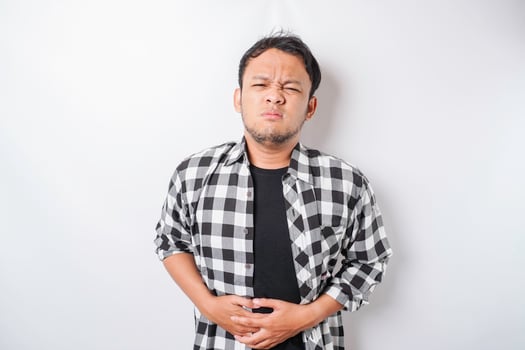 Photo of young unwell sick ill man hold hand on stomach suffers pain isolated on white background