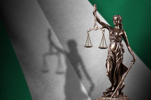 Nigeria flag with statue of lady justice and judicial scales in dark room. Concept of judgement and punishment photo