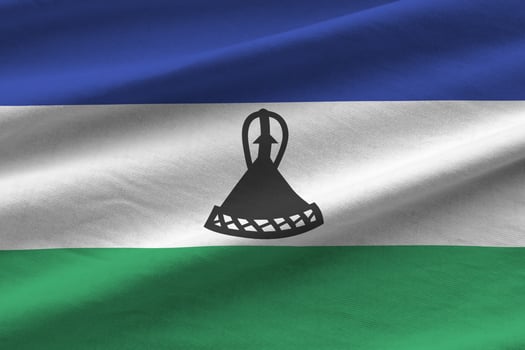 Lesotho flag with big folds waving close up under the studio light indoors. The official symbols and colors in banner photo