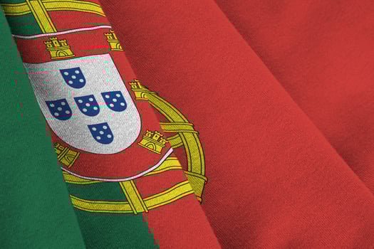 Portugal flag with big folds waving close up under the studio light indoors. The official symbols and colors in banner photo