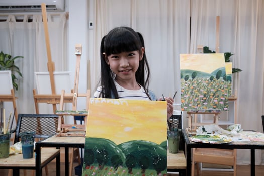 One Asian student girl shows her painting work, proud with portfolio, acrylic color picture on canvas in art classroom and creative learning with talents skill at elementary school studio education. photo