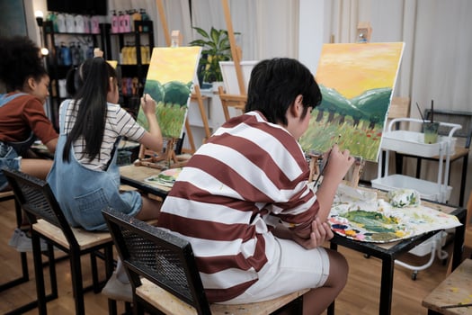 A group of student kids concentrates on acrylic color picture painting with a paintbrush on canvas in art classroom, creatively learning with talents and skills at elementary school studio education. photo