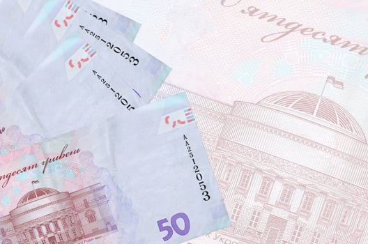 50 Ukrainian hryvnias bills lies in stack on background of big semi-transparent banknote. Abstract business background photo
