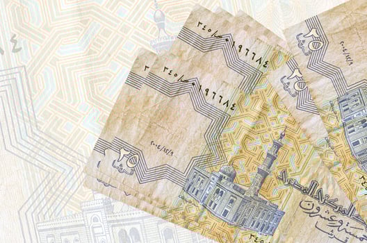 25 Egyptian piastres bills lies in stack on background of big semi-transparent banknote. Abstract presentation of national currency photo