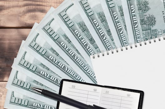 100 US dollars bills fan and notepad with contact book and black pen. Concept of financial planning and business strategy photo