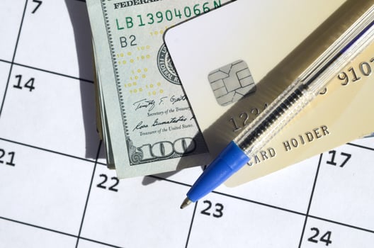 Pen and credit card on many hundred US dollar bills on calendar page close up photo
