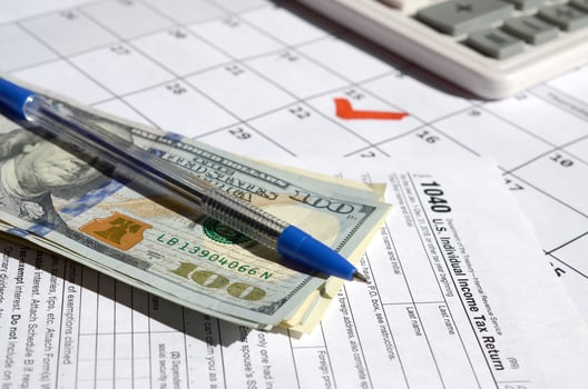 1040 Individual Income Tax Return blank with dollar bills, calculator and pen on calendar page with marked 15th April photo