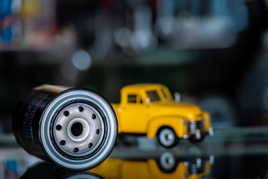 Engine oil lubricant filter with yellow truck car background in the store, Automotive auto parts maintenance service concept. photo