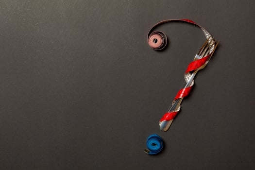 Top view of question mark made of fork and measuring tape on black background. Diet concept with copy space photo