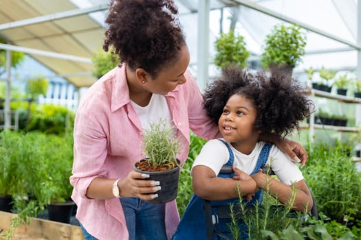 African mother and daughter is choosing vegetable and herb plant from the local garden center nursery with shopping cart full of summer plant for weekend gardening and outdoor concept photo
