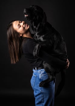 A girl holds a Labrador Retriever dog in her arms. photo
