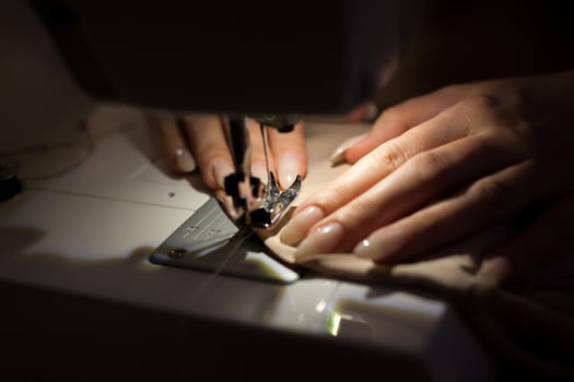 The woman is sewing with sewing machine. Sewing is one of the oldest of the textile arts. photo
