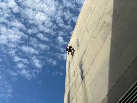 painter fixing the wall and painting on the wall of the building Construction worker with a roller brush work on tall buildings without safety equipment The concept of dangerous work at heights photo