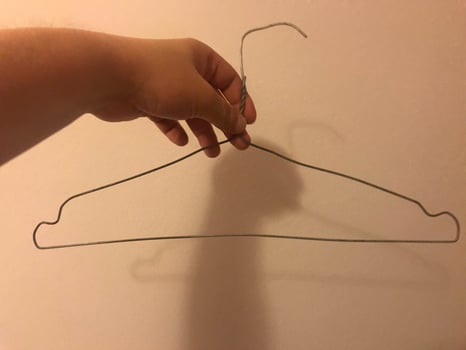 Homemade clothes hanger made of wire. Poor clothes rack in a cheap hotel room photo