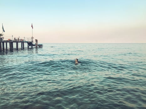 girl with dark hair swims in the sea. mermaid swims in the ocean. rest on vacation. cruise. the girl swims far behind the buoys. against the background of the waves and blue sky photo