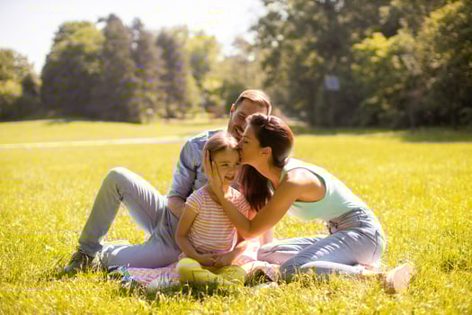 Happy young family with cute little daughter having fun in the park on a sunny day photo