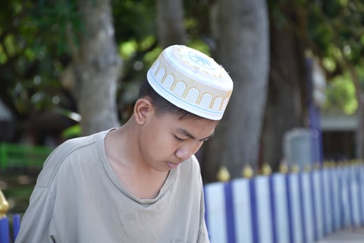 Portrait young southeast asian islamic or muslim boy in white shirt and hat, isolated on white, soft and selective focus. photo