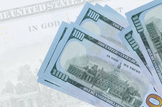 100 US dollars bills lies in stack on background of big semi-transparent banknote. Abstract presentation of national currency photo