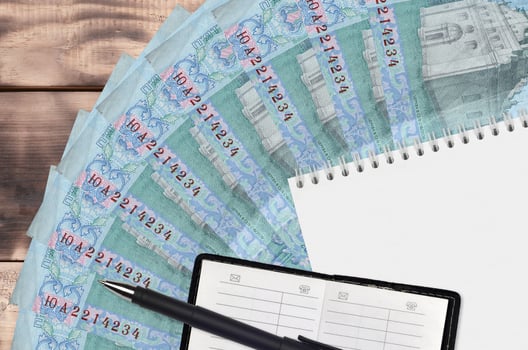 5 Ukrainian hryvnias bills fan and notepad with contact book and black pen. Concept of financial planning and business strategy photo