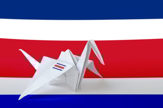 Costa Rica flag depicted on paper origami crane wing. Handmade arts concept photo