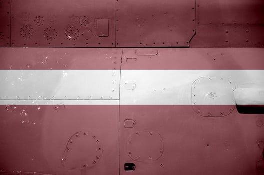 Latvia flag depicted on side part of military armored helicopter closeup. Army forces aircraft conceptual background photo