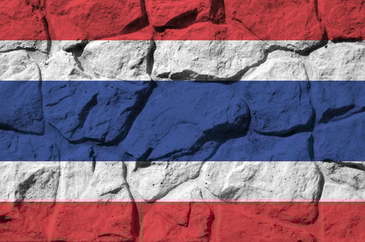 Thailand flag depicted in paint colors on old stone wall closeup. Textured banner on rock wall background photo