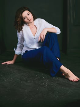 Portrait of young, beautiful sad actress with short brown hair in white shirt and blue pants in the studio photo