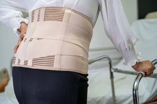 Asian lady patient wearing back pain support belt for orthopedic lumbar with walker. photo