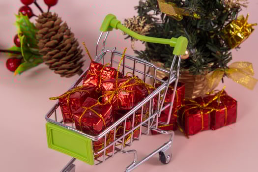 Christmas shopping cart with gifts and Christmas tree in background photo