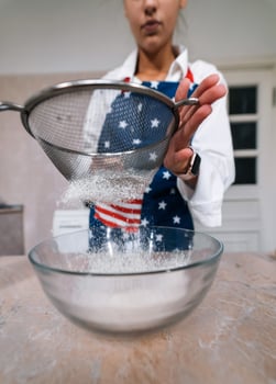 Woman sifting flour through sieve. Selective focus. photo