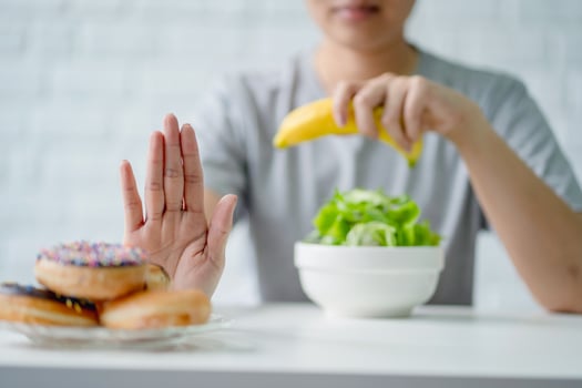 Young woman rejecting junk food or unhealthy food such as donut and choosing healthy food such as green apple and salad for her health. photo