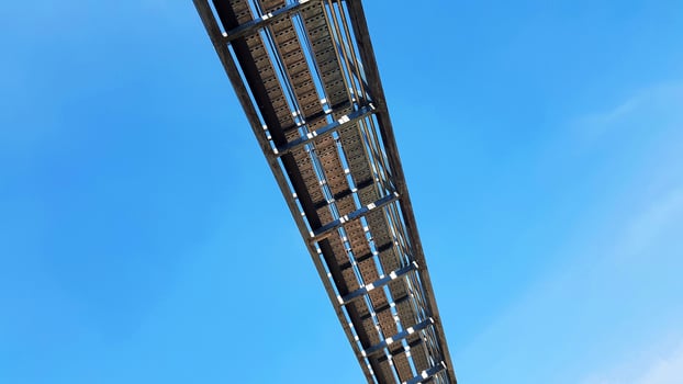 Bottom view of stainless steel electrical or communication cable tray with clear blue sky background with copy space. Iron bridge cross to air or heaven and industrial and installed system concept. photo