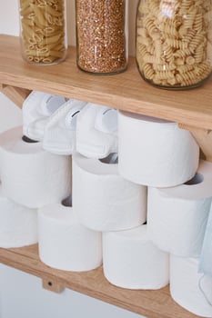 Stocks of a toilet paper rolls, protective mask and products on shelf at home photo