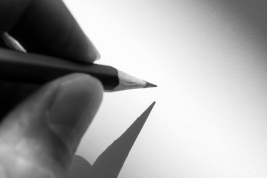 Human's hand holding pencil to write on the paper in shadow photo